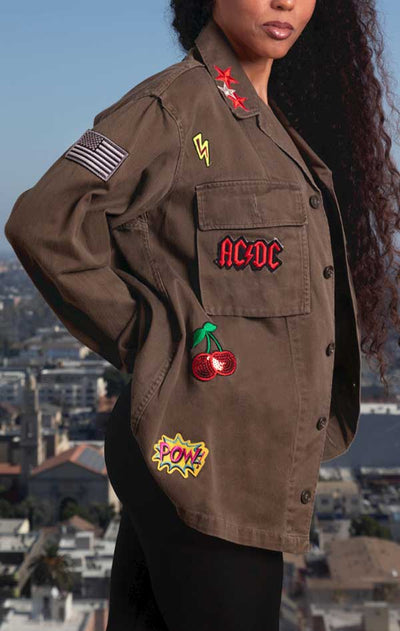 Female models side view of CdJ RockStar jacket in solid khaki with music patch embellishments. 
