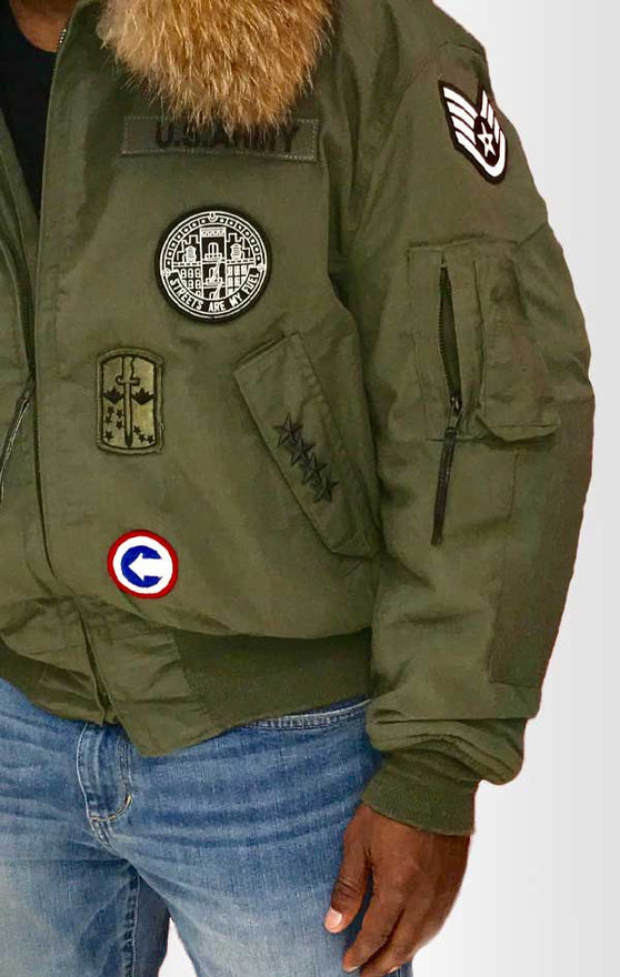 Male models front/side view of CdJ Furbomb jacket. Bomber-style army-green jacket with embellishments.