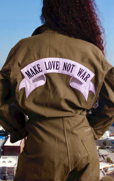 Female models back view of CdJ Olive Drab jumper with "Make Love Not War" patch emblazoned on the back. 