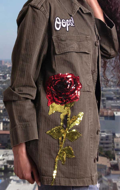 Female models side view of CdJ Olive Drab jacket with large sequin rose embellishment. 